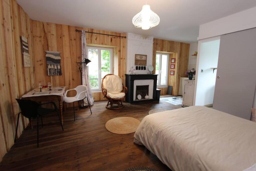 a bedroom with a bed and a table and a fireplace at Charmant studio avec jardin à la campagne sur le chemin de Saint Jacques de Compostelle in Lauzerte