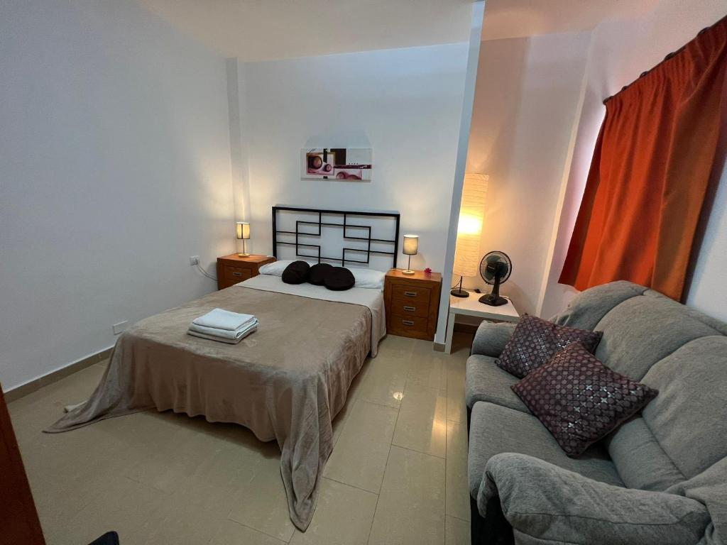 un dormitorio con una cama y un sofá en Alquiler de Habitación privada con baño compartido cerca al Mar!, en Alcalá