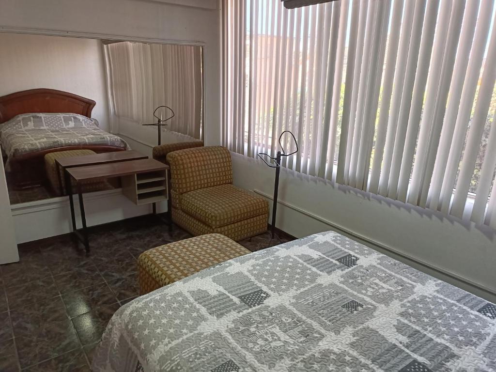 1 dormitorio con 1 cama, 1 mesa y 1 silla en SUITE PB101 - A 5 MINUTOS DEL CENTRO HISTORICO, en Quito