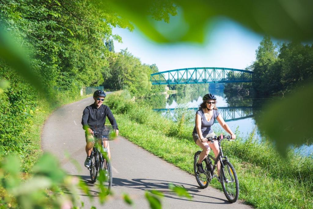 two people riding bikes down a path next to a river at Le Bellevue in Givet