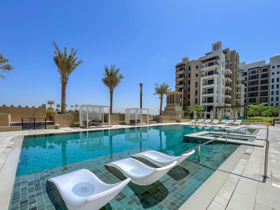 a swimming pool with white chairs and some buildings at Vogue Jumeirah Living - Near Burj Al Arab & Beach in Dubai