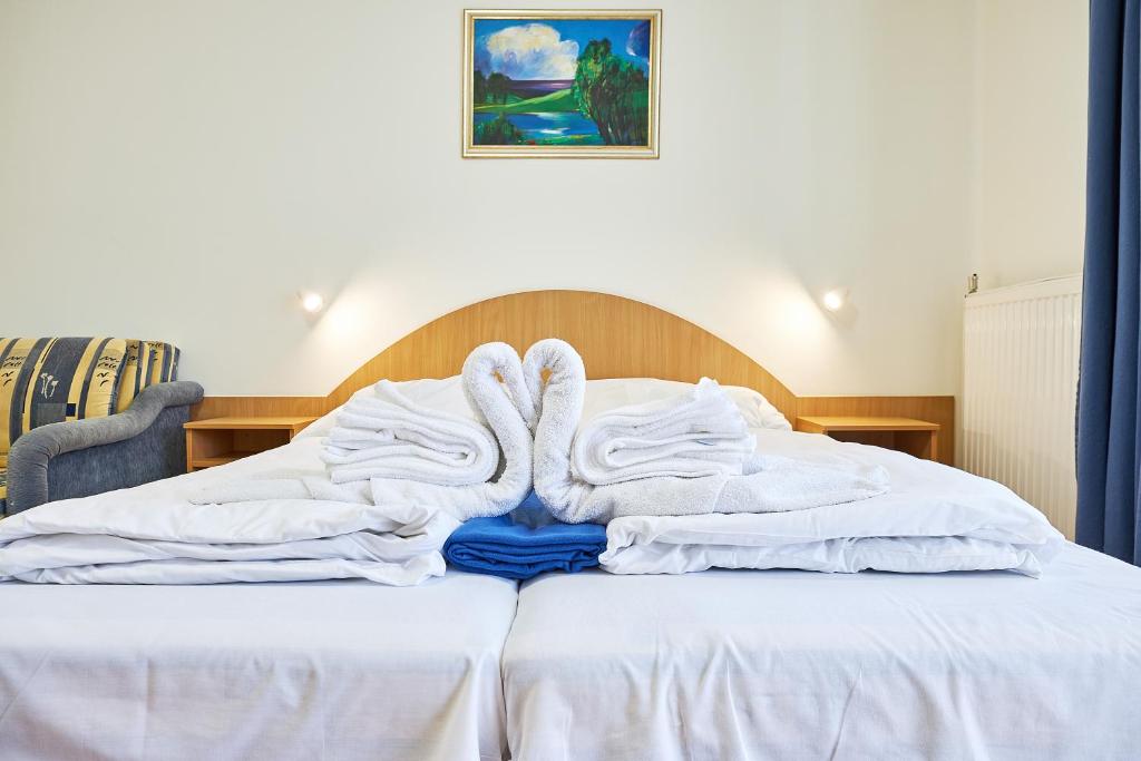 a bed with white blankets and towels on it at Nimród Vendégház in Hajdúszoboszló