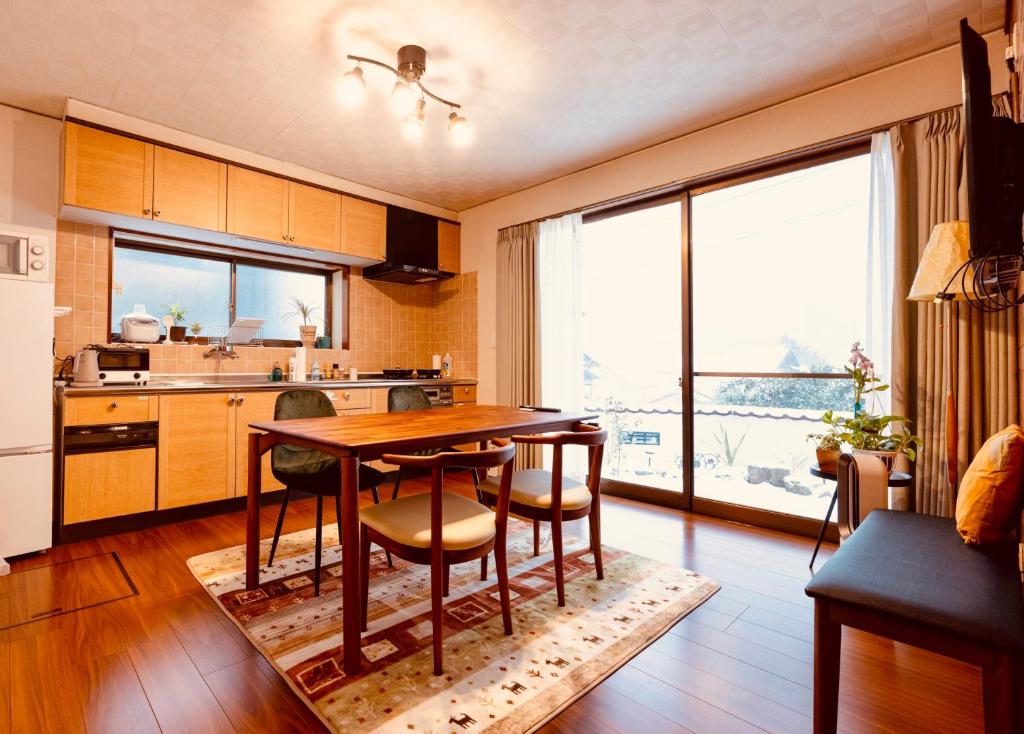 uma cozinha com mesa e cadeiras e uma grande janela em 湯庵 完全貸し切り庭付き em Matsue