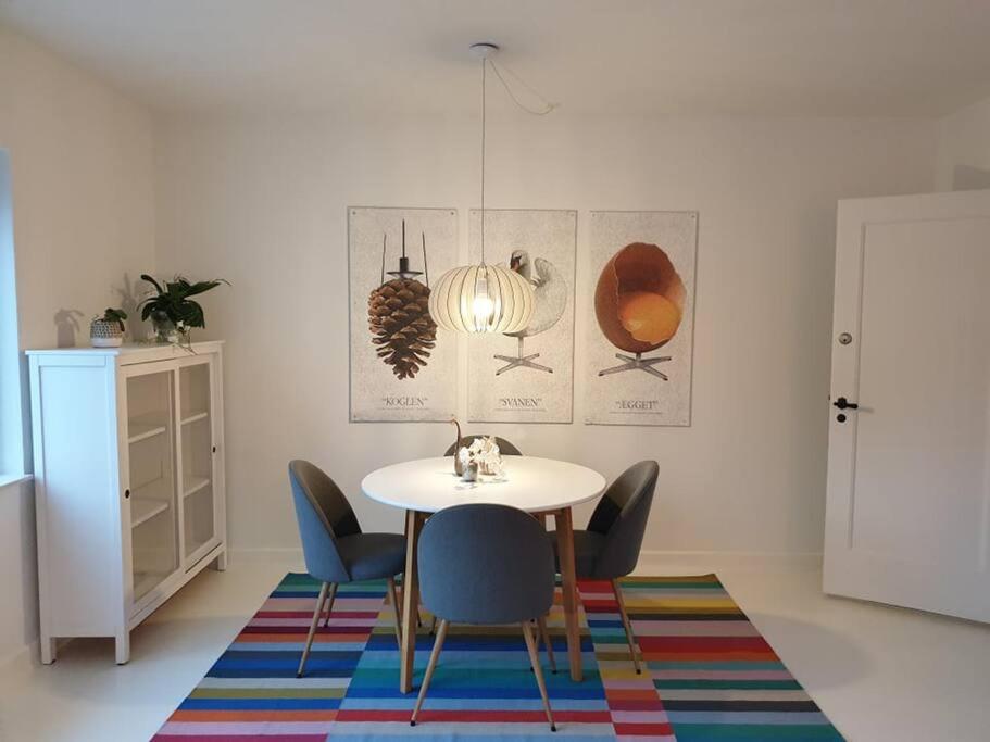 a dining room with a table and chairs on a rug at Charmerende lejlighed i Viby in Viby