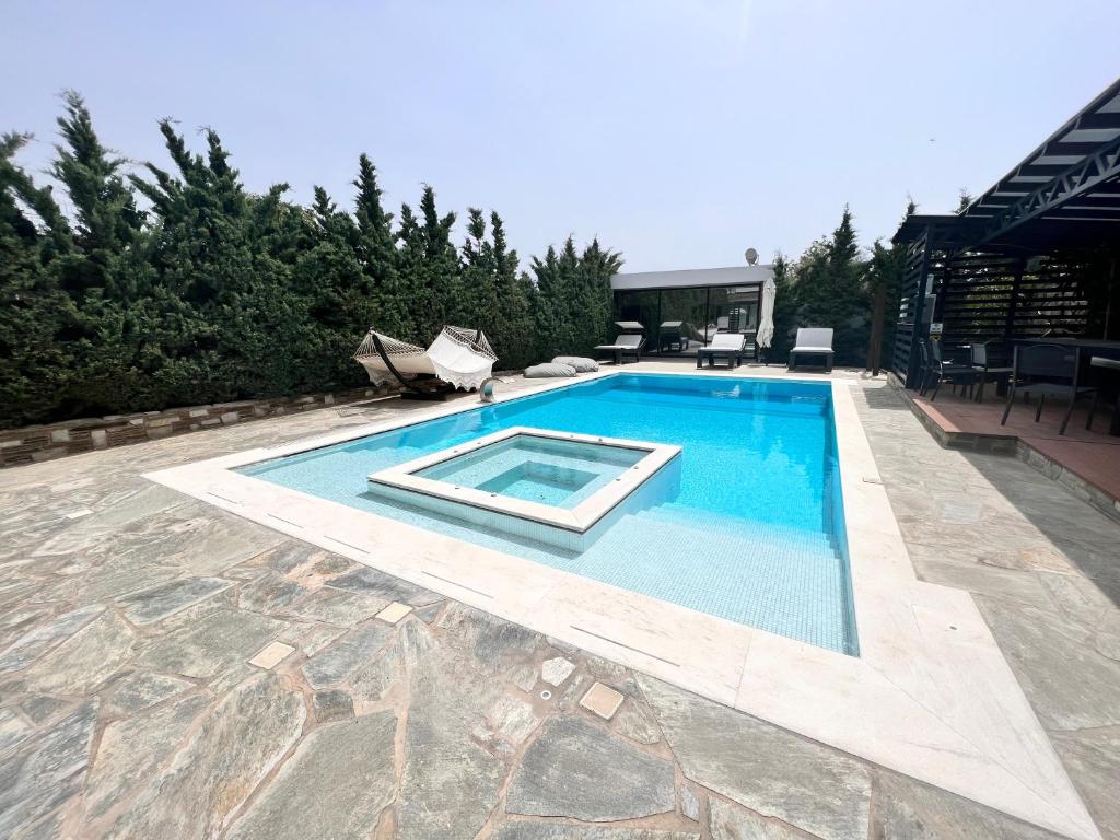 ein Schwimmbad in der Mitte eines Gartens in der Unterkunft Olivujoj Villajoj - Deluxe Villa with Detached Pool House in Anavyssos