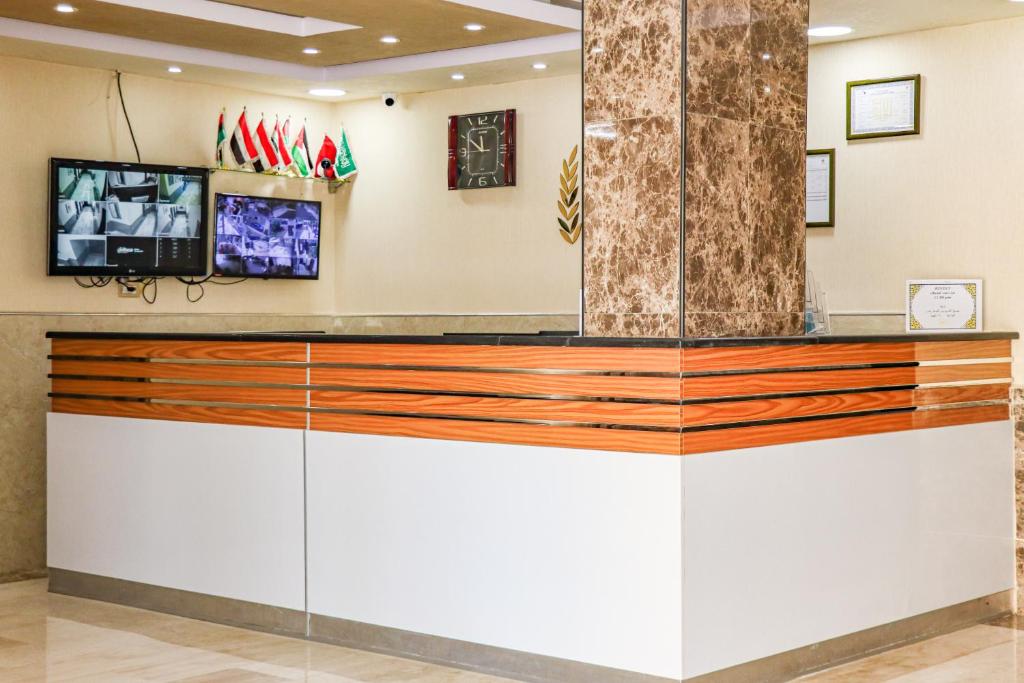 a lobby with a counter with a tv on the wall at Al Jamal Suites in Amman