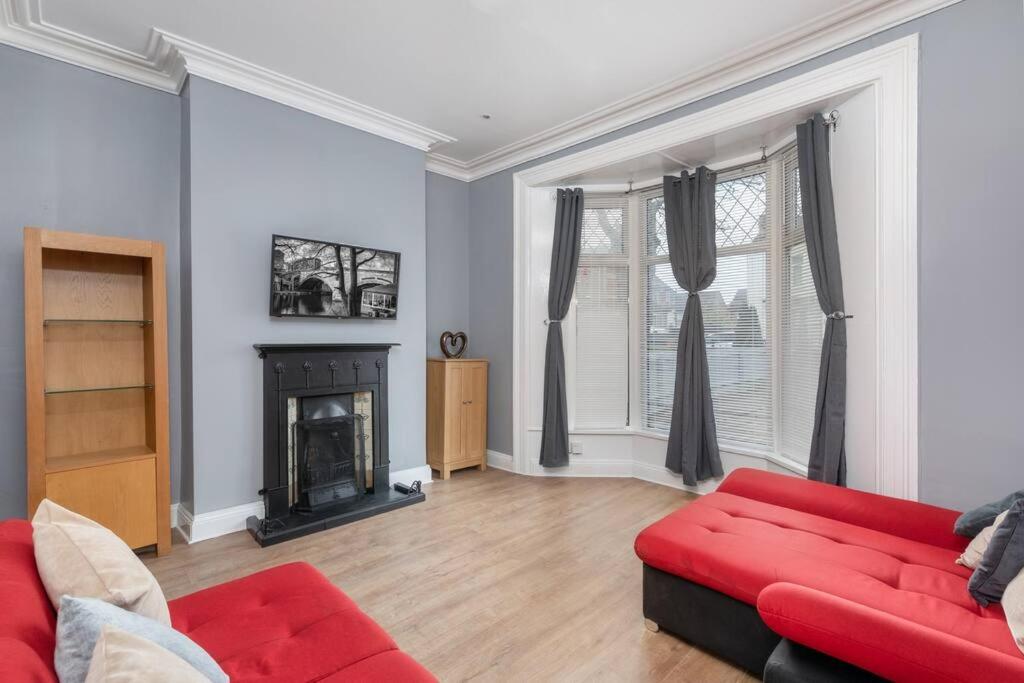 a living room with a red couch and a fireplace at Large Parade Coastal House in Hartlepool