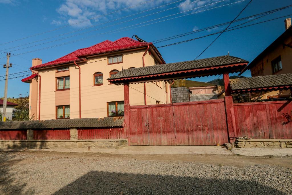 una casa con una valla roja y un edificio en Pensiunea Agroturistica Stefan Viorica, en Moldoviţa