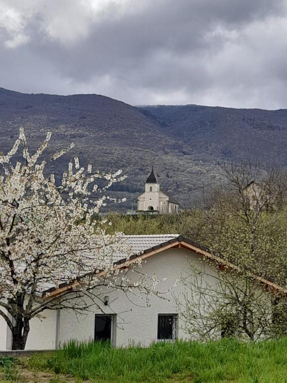 a white building with a church in the background at Au fond du village in Bassy