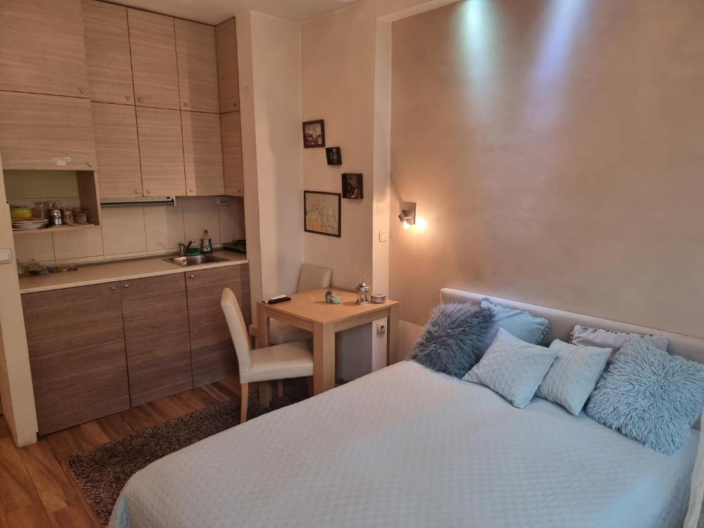 a bedroom with a bed and a table and a kitchen at Apartment Bombonjera in Užice