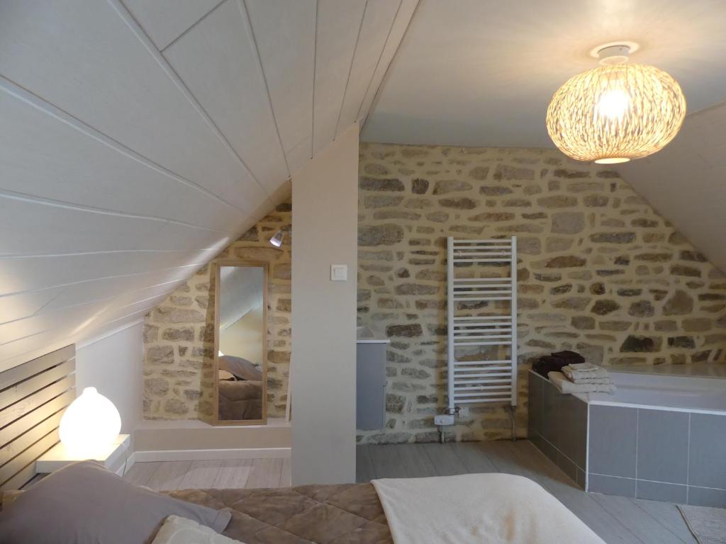 a bedroom with a stone wall with a bed and a chandelier at Espace Acu-Nature in Saint-Évarzec