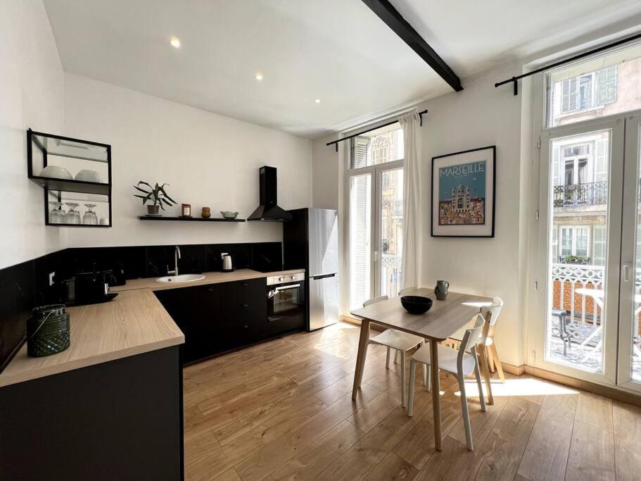 ein Wohnzimmer mit einem Tisch und einer Küche in der Unterkunft T2 balcon Hyper centre - Paradis in Marseille