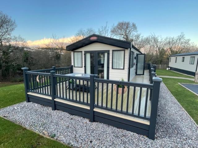 a small house with a black and white fence at 3 bed luxury lodge at Hoburne Devon Bay in Goodrington