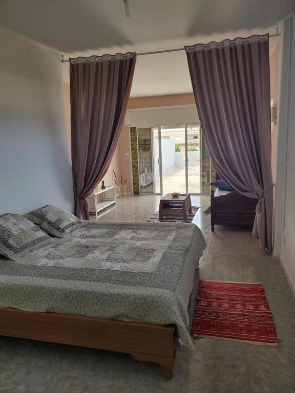 - une chambre avec un grand lit et des rideaux violets dans l'établissement Beau duplex Haouaria, à El Haouaria