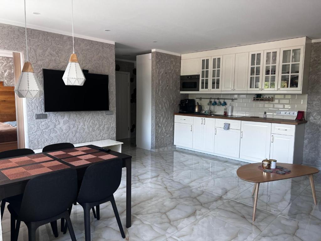 eine Küche mit weißen Schränken sowie einem Tisch und Stühlen in der Unterkunft Rotušės apartamentai Kretingoje in Kretinga