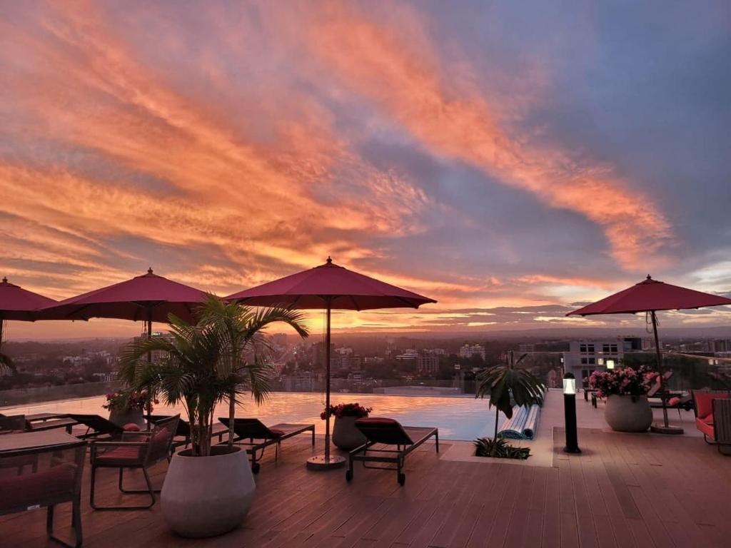 un toit-terrasse avec des tables et des parasols et un coucher de soleil dans l'établissement Skynest Residences by Lisa's Paradise A, à Nairobi