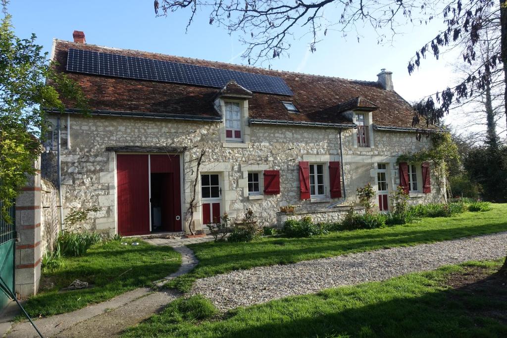 una vecchia casa in pietra con pannelli solari sul tetto di les épis de la joie a Ligueil