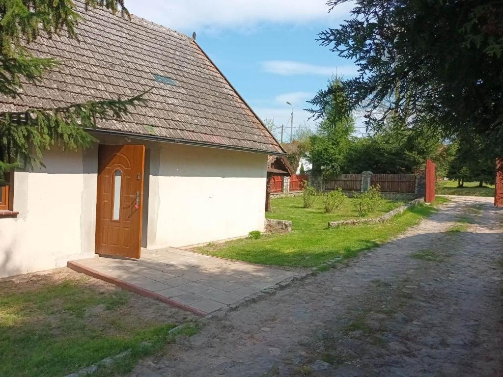 a small white building with a brown door on a street at Sielski Zakątek in Srokowo