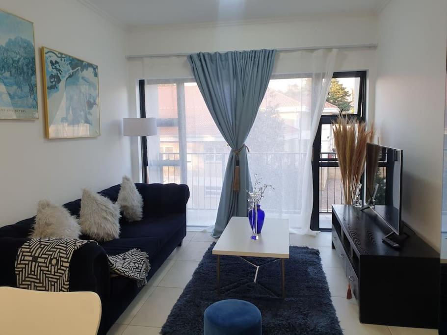 a living room with a blue couch and a table at Sophiscated Upmarket One Bedroom Apartment in Johannesburg