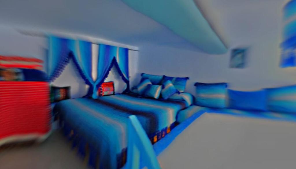 a blue room with two beds and a couch at The blue in Chefchaouen