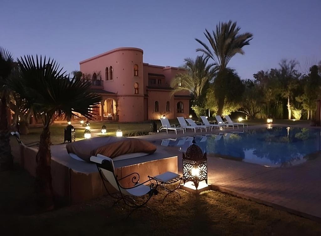 une maison dotée d'une piscine avec un lit et des chaises dans l'établissement Dar Moulouya, à Marrakech