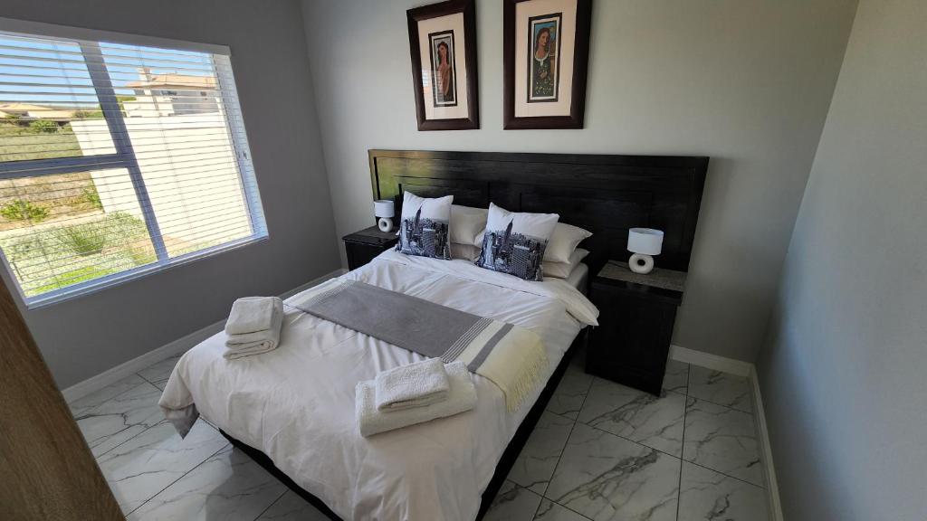 um quarto com uma cama grande com lençóis brancos e almofadas em One Bedroom Unit with Kitchenette in Langebaan Country Estate - Solar Power em Langebaan