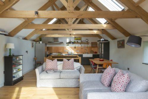 sala de estar con 2 sofás y cocina en The Threshing Barn, en Loddiswell