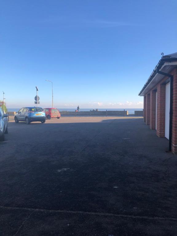 ein Parkplatz mit Autos vor dem Meer in der Unterkunft Beach Front House in Walton-on-the-Naze