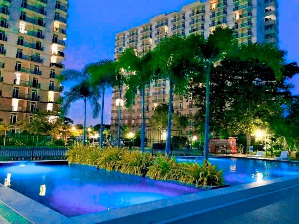 einem Pool mit Palmen vor einem Gebäude in der Unterkunft Condo Near Mactan Airport in Cebu City