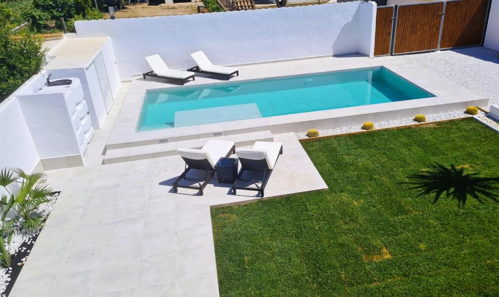 a backyard with a swimming pool with chairs and a lawn at Villa Turquesa in Zahora