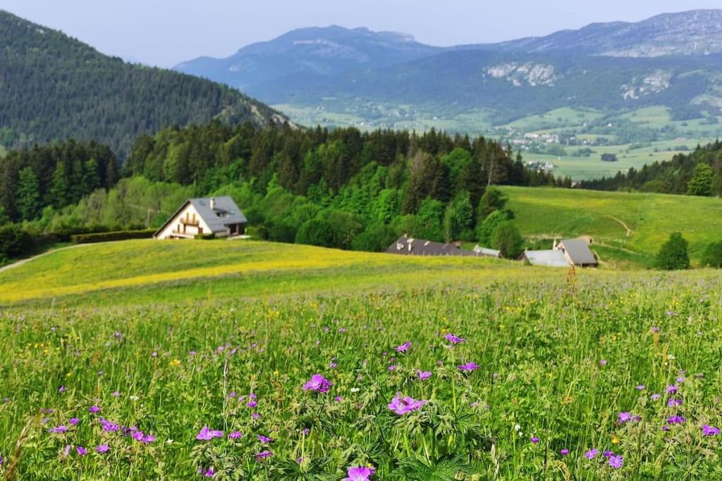 un champ de fleurs dans un champ avec une maison dans l'établissement appartement de détente dans le Vercors 4-6 max, à Villard-de-Lans
