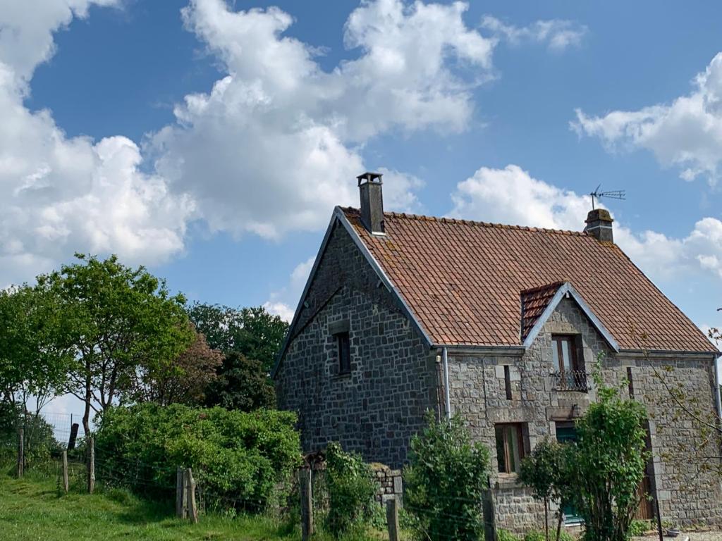 una antigua casa de piedra con techo rojo en Gîte des Pommiers, en Le Fresne-Poret