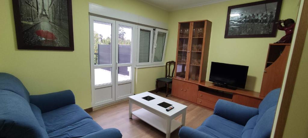 sala de estar con 2 sofás azules y TV en Bruma, en Barreiros