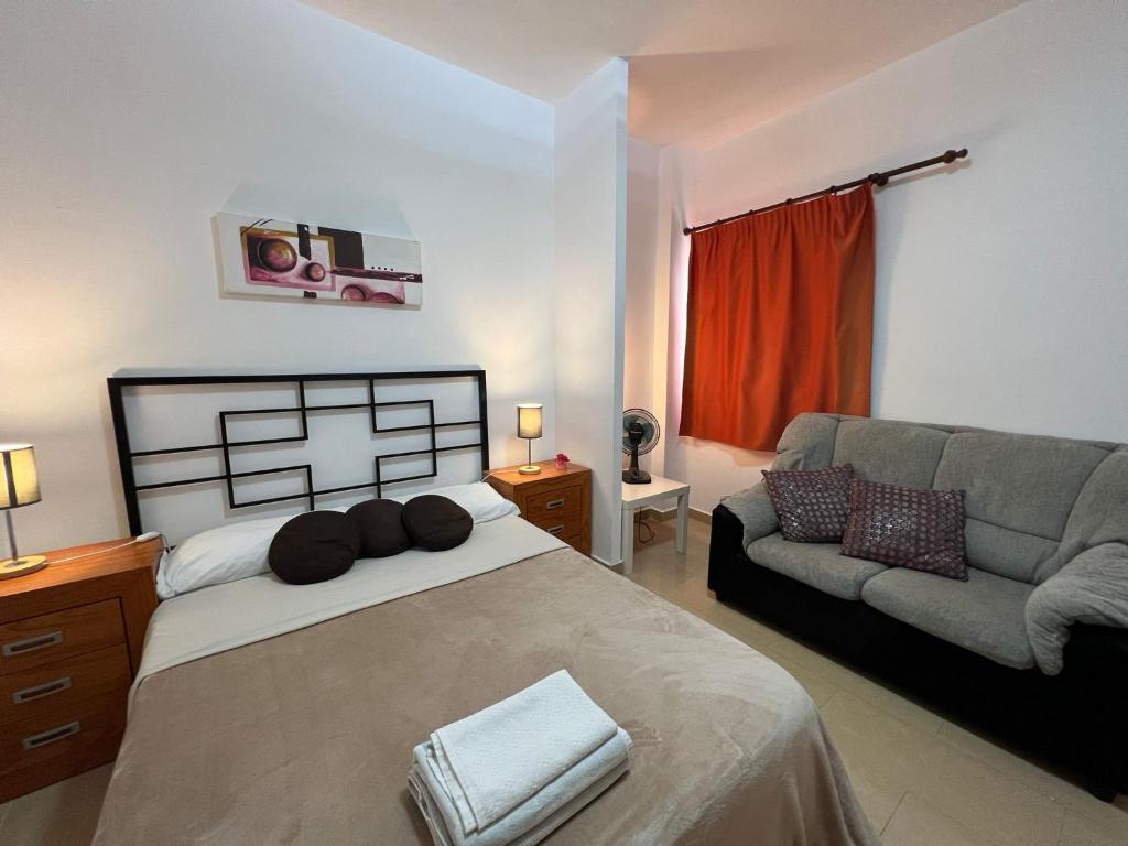 ein Schlafzimmer mit einem großen Bett und einem Sofa in der Unterkunft ALCAMAR Alquiler de Habitaciones con cocina y baño compartido y balcón con vista al mar! in Alcalá