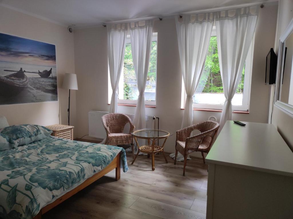 a bedroom with a bed and a table and windows at Kamionka in Sopot