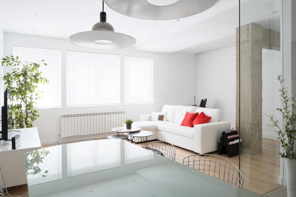 a white living room with a white couch and red pillows at CARPE DIEM - Disfruta a lo grande in Pamplona