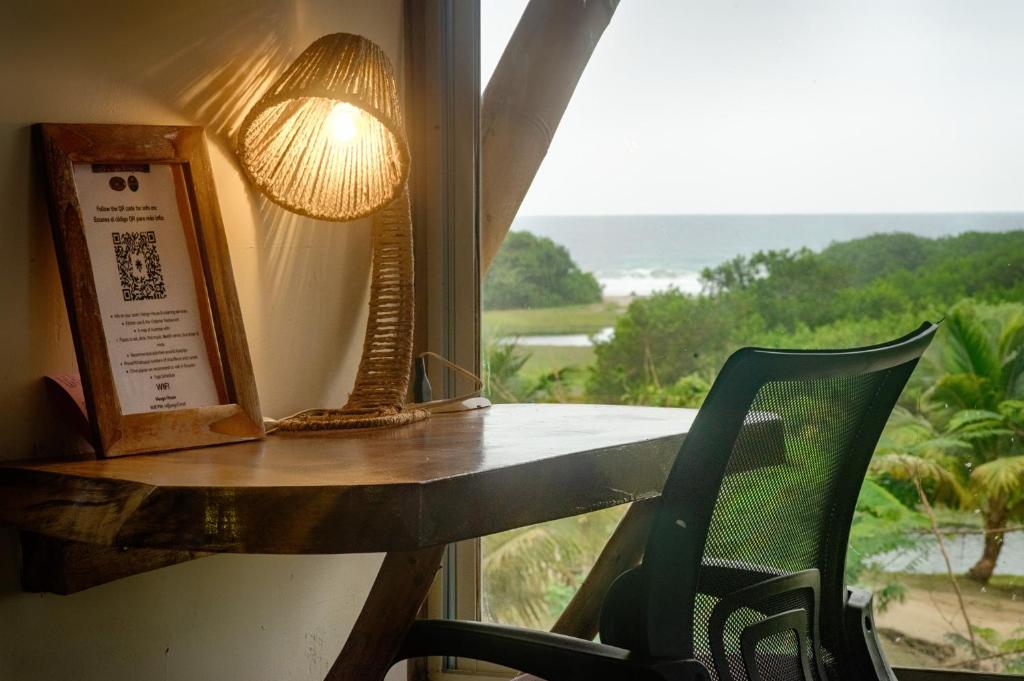 Vistamar Guest House في أيامبي: طاولة مع مصباح وكرسي بجوار النافذة
