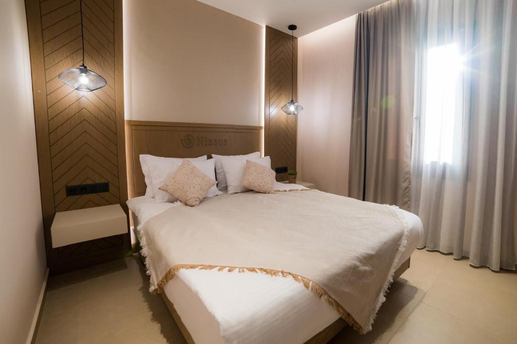 a bedroom with a large white bed and a window at Nissos Apartments in Myrina
