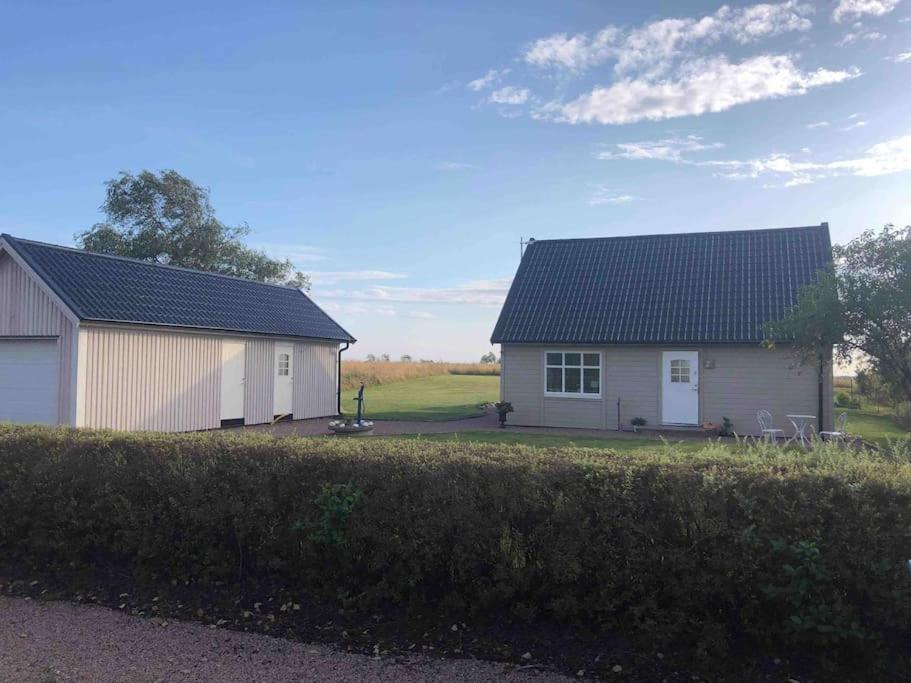 a white house with a black roof in a yard at Modern house, views over the fields 5 min to beach in Halmstad