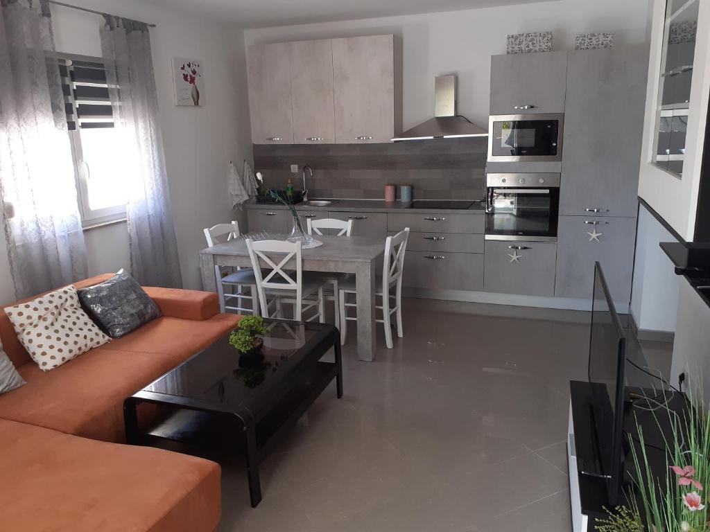 a living room with a couch and a table and a kitchen at Apartman Nada in Ližnjan