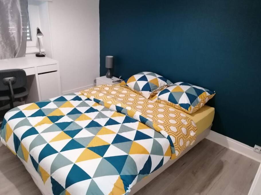 una camera con un letto con una parete blu di Appartement meublé proche du centre - Wifi/Parking a Clermont-Ferrand