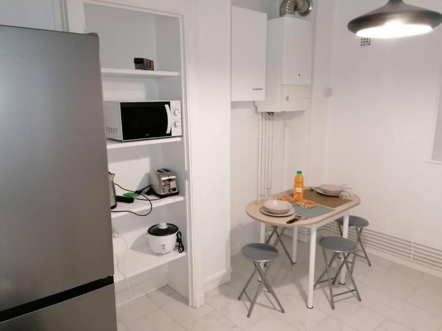 a small white kitchen with a table and chairs at Appartement meublé proche du centre - Wifi&#47;Parking in Clermont-Ferrand
