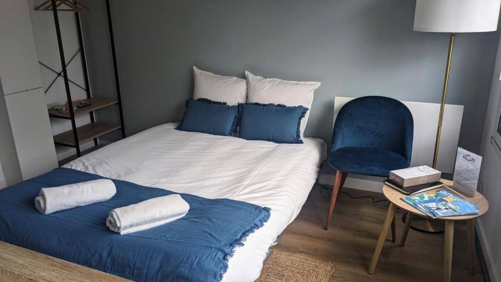 Una cama con almohadas azules y una silla en una habitación. en Appartements au Cœur de Maine en Angers