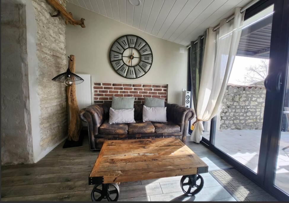 un soggiorno con divano e orologio sul muro di Sublime maison - LA PERLA a Meschers-sur-Gironde