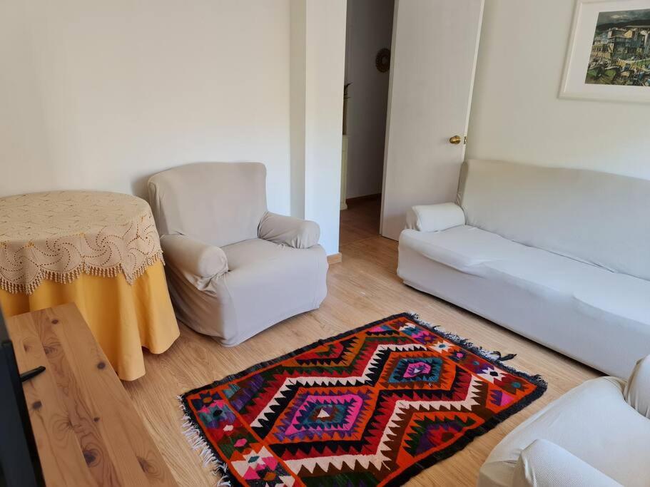 un soggiorno con tavolo, sedia e tappeto di Casa Roge a Luarca