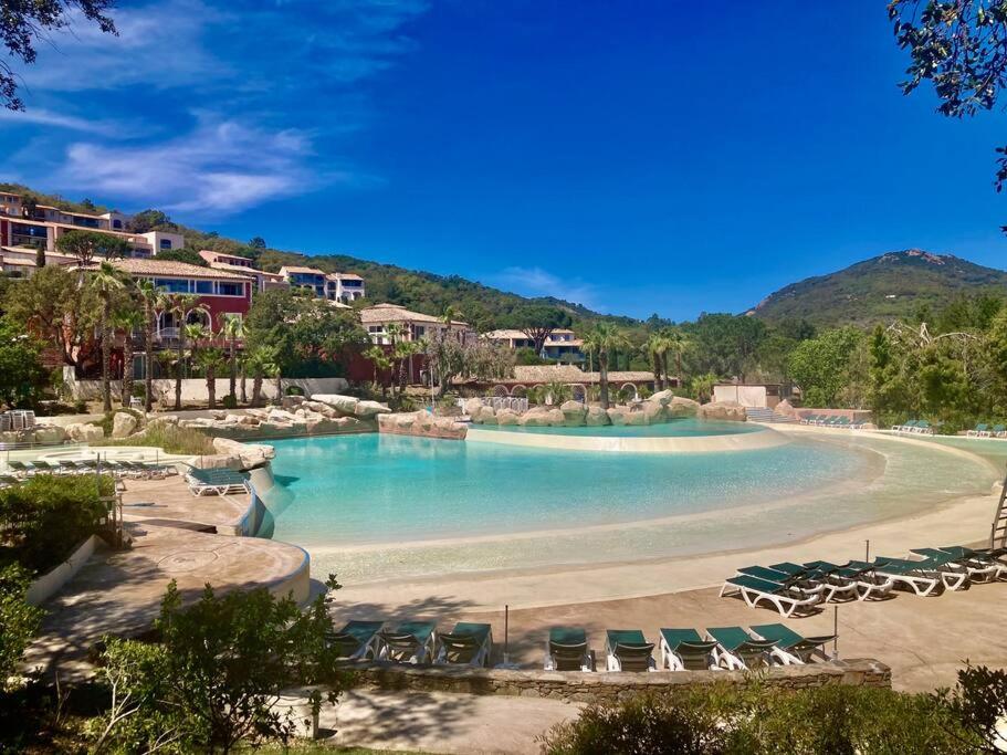 een groot zwembad met stoelen en een strand bij Les Restanques glycines 2066 in Grimaud