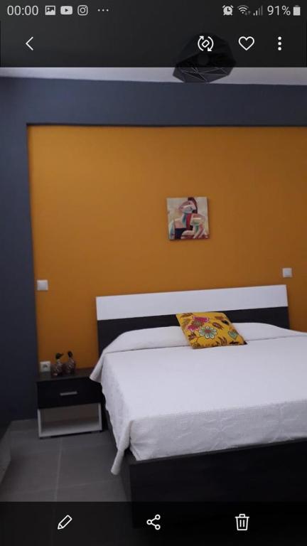ein Schlafzimmer mit einem Bett mit einer orangefarbenen Wand in der Unterkunft Kostas apartament in Kontokali
