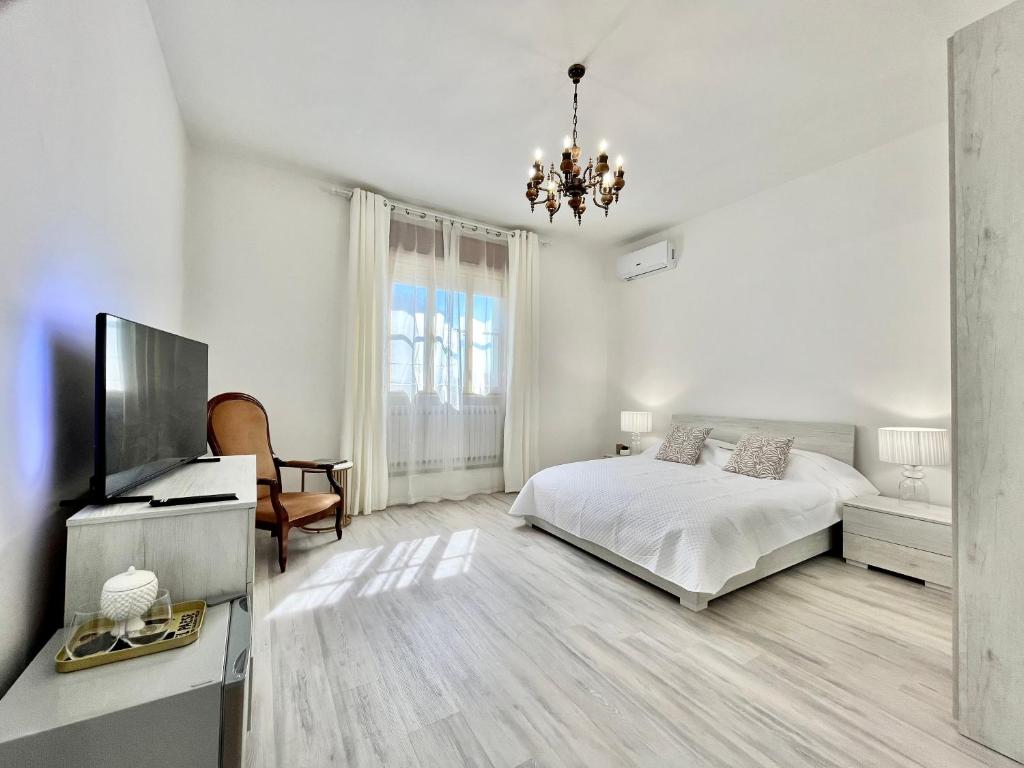 ein weißes Schlafzimmer mit einem Bett und einem Flachbild-TV in der Unterkunft La Villetta nel Delta in Mesola