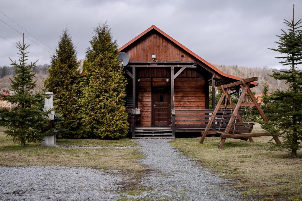 uma cabana de madeira com um alpendre e um baloiço em Domek na zacisznych obrzeżach Kazimierza Dolnego em Kazimierz Dolny