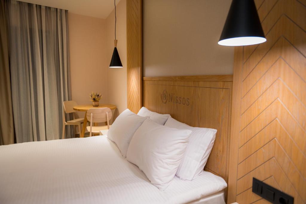 a bedroom with a bed with white pillows and a table at Nissos Apartments in Myrina